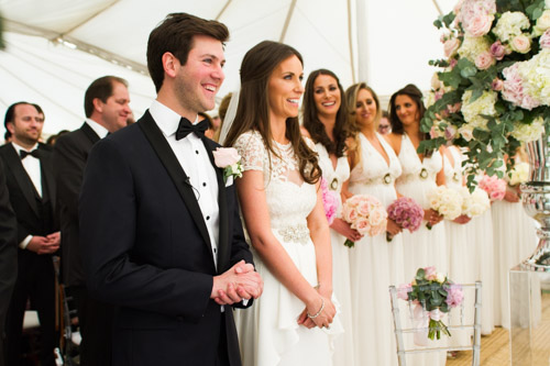 bride and groom laughing during their elegant wedding ceremony full of rose and cream flowers at the grove in hertfordshire