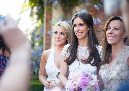 elegant bride in a temperley bluebell dress during her reception with her mom and sister in a candid moment outside the grove in hertfordshire