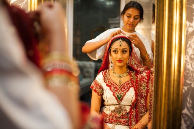 hindu bride getting ready and fixing her dress in front of a mirror before her ceremony at premier banqueting london