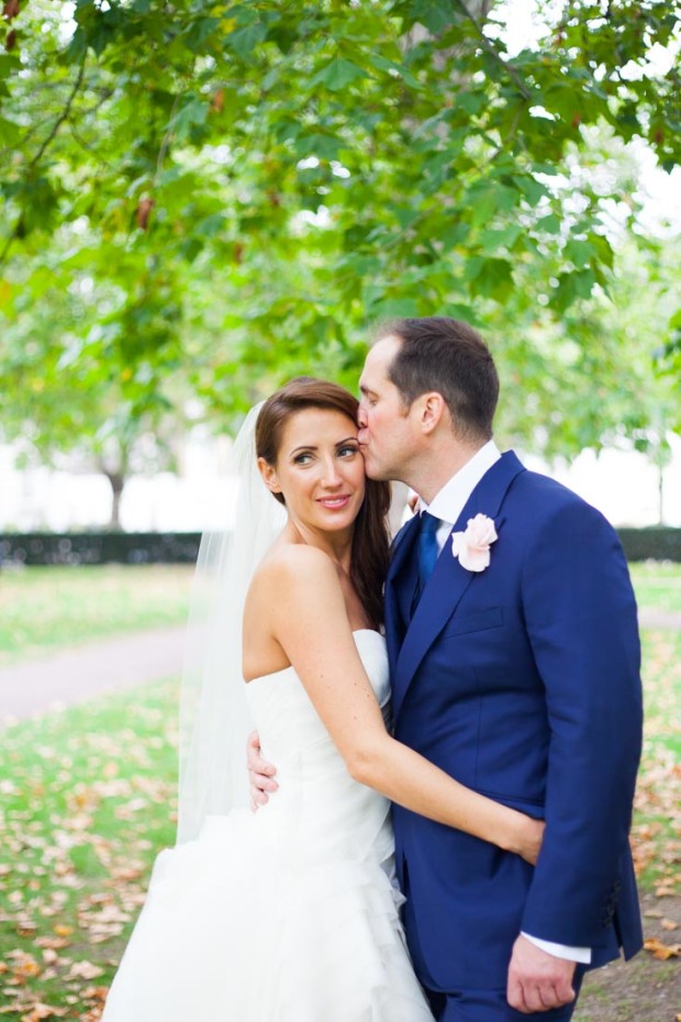 bride kissing his bride and cuddling during their wedding portraits in mayfair london with a vera wang dress