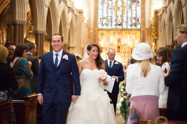 chic bride and groom walking towards the end of their church smiling on their wedding day in mayfair london