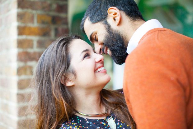 romantic couple portraits while they laugh in a natural and spontaneous way at each other in holland park london during their engagement session