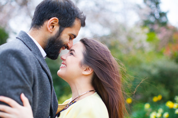 a couple naturally smiling at each others head on head during their engagement session in holland park in london