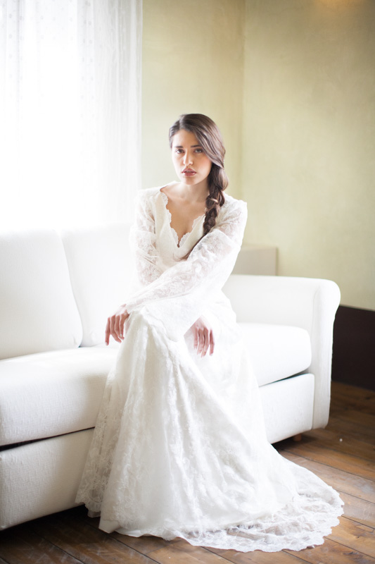 editorial and fine art wedding portrait of an italian bride during her preparation while she is on the couch in her rustic bridal suite in italy