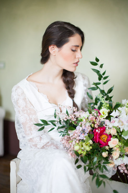 organic bridal portrait of an italian bride with a braid holding a deconstructed bouquet in her bridal suite in italy