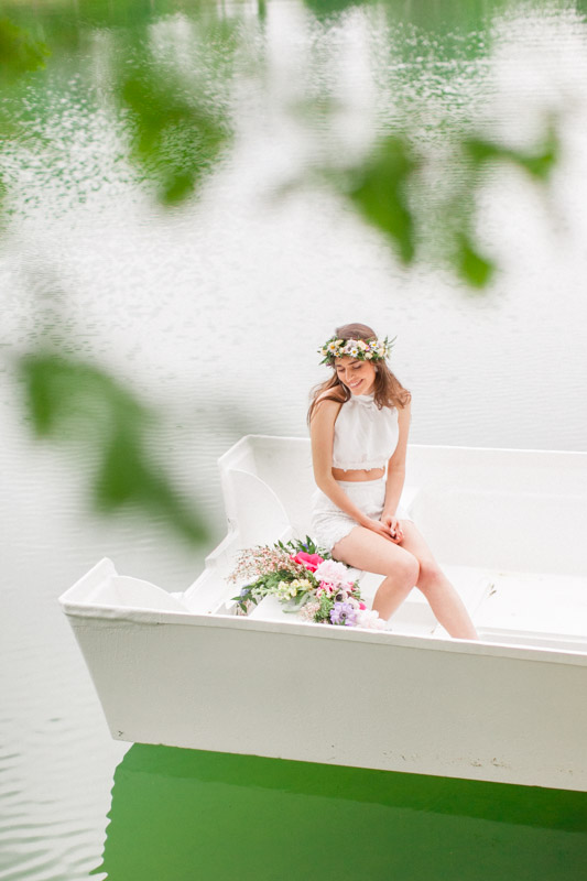 italian bride with a floral crown dressed in white on a small white boat on a lake in urbino italy