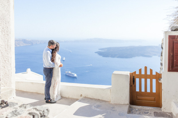 greek bride and groom staring at the view in santorini of the caldera during their wedding portraits