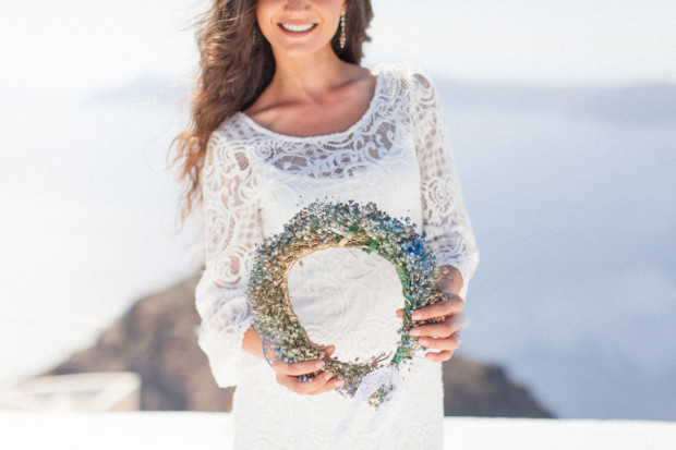 greek bride holding her floral crown during her wedding portraits in santorini greece