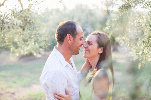 natural smile of an italian couple on the olive field during their engagement session in apulia, italy with a soft and back light