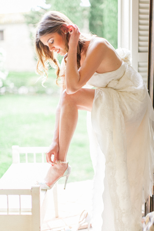 intimate moment of a chic bride before her wedding ceremony while she wears her luxury wedding shoes in italy at urbino resort in the marche region