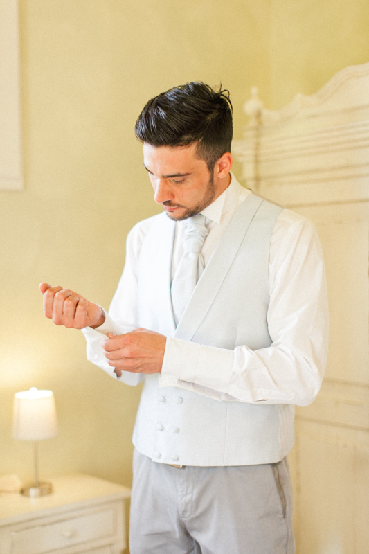 groom getting ready before his wedding day in a rustic room of the urbino resort in italy