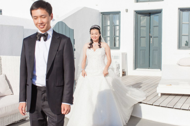 a second before the first look, while the bride exit her hotel room and walks towards her chinese groom before their destination wedding in santorini greece