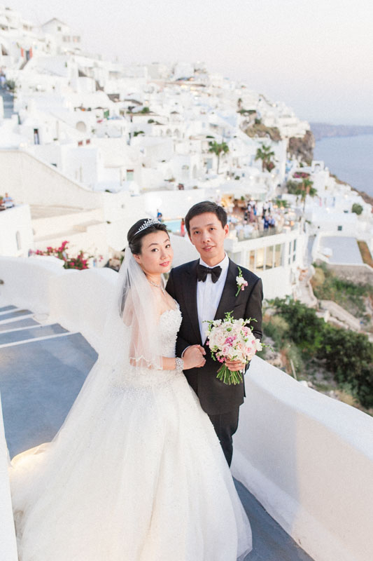 portrait of a chinese bride and groom on their wedding day in the village of firostefani in santorini greece after their wedding ceremony at the sun rocks hotel