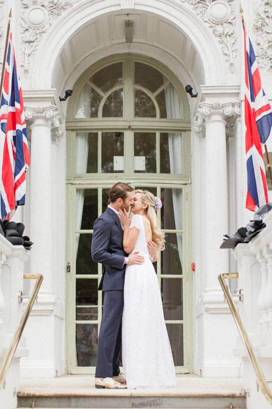 bride and groom kissing at the entrance of the loggia of the mandarin oriental hotel in london during their wedding day